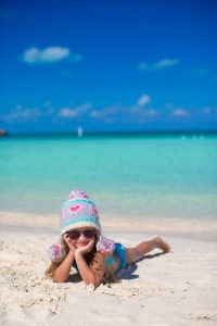 Bébé de 10 mois assis sur une plage des Caraïbes avec ses parents.