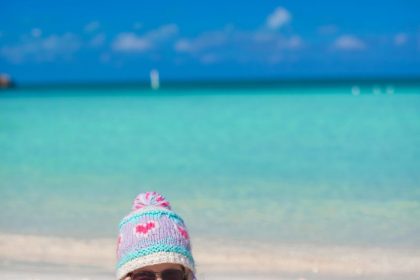 Bébé de 10 mois assis sur une plage des Caraïbes avec ses parents.
