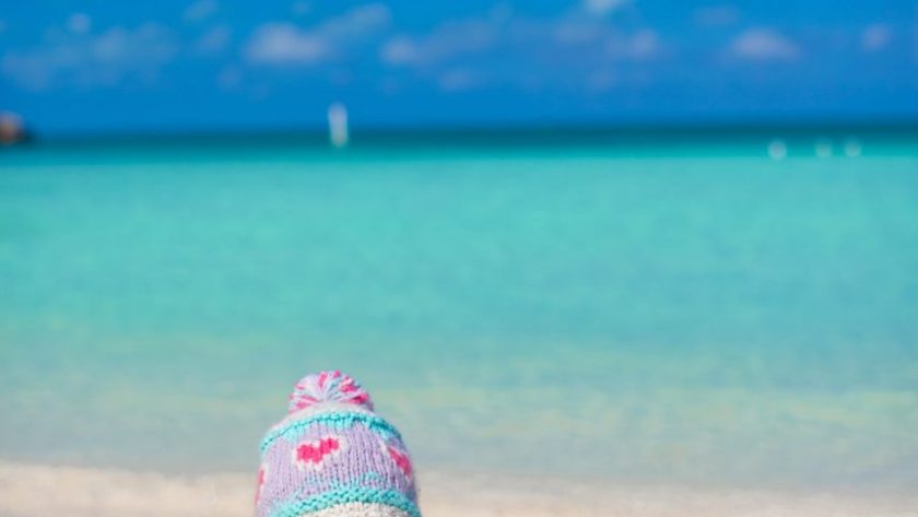 Bébé de 10 mois assis sur une plage des Caraïbes avec ses parents.
