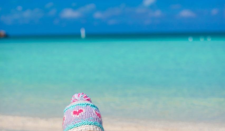 Bébé de 10 mois assis sur une plage des Caraïbes avec ses parents.