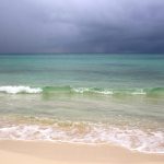 Plage des Caraïbes sous un ciel chargé de nuages avant une tempête tropicale.