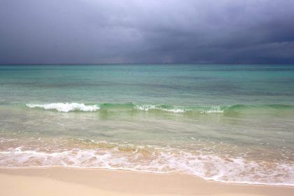 Plage des Caraïbes sous un ciel chargé de nuages avant une tempête tropicale.