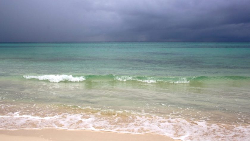 Plage des Caraïbes sous un ciel chargé de nuages avant une tempête tropicale.