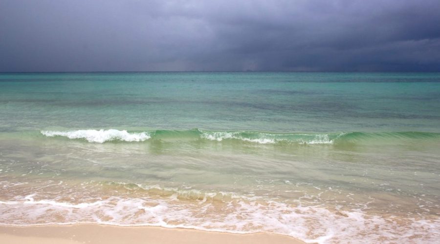 Plage des Caraïbes sous un ciel chargé de nuages avant une tempête tropicale.