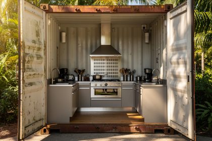 Cuisine d’été aménagée dans un conteneur maritime ouvert sous les tropiques, avec hotte en inox, grilles de ventilation et lumière naturelle.