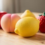 Gros plan de plusieurs squishies en forme de fruits, à texture douce et mousse dense, posés sur une table claire sous une lumière naturelle délicate.