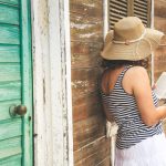 Voyageur vérifiant une maison d’hôtes colorée dans les Caraïbes avec un propriétaire local.