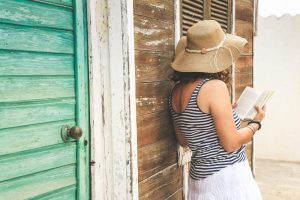 Voyageur vérifiant une maison d’hôtes colorée dans les Caraïbes avec un propriétaire local.