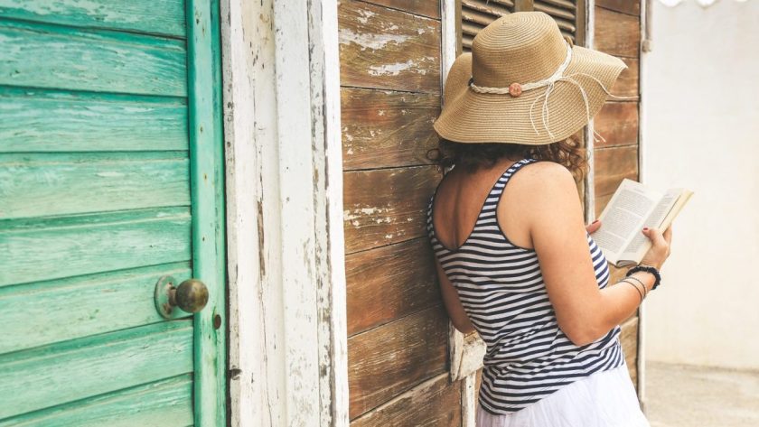 Voyageur vérifiant une maison d’hôtes colorée dans les Caraïbes avec un propriétaire local.